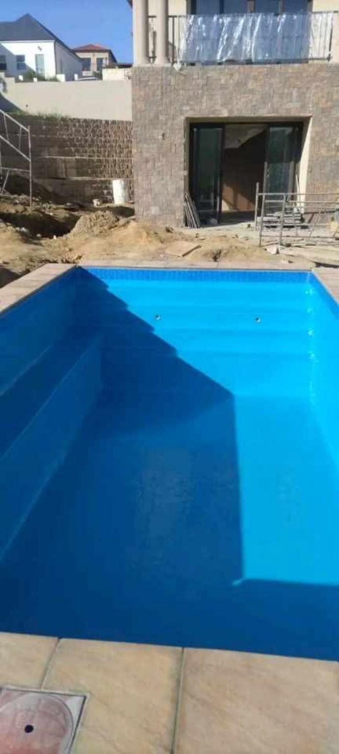 Blue residential swimming pool beside modern home